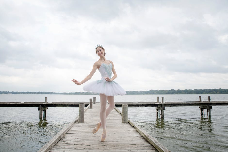 A serene woman in a white outfit performs a yoga pose on a wooden pier by the lake.